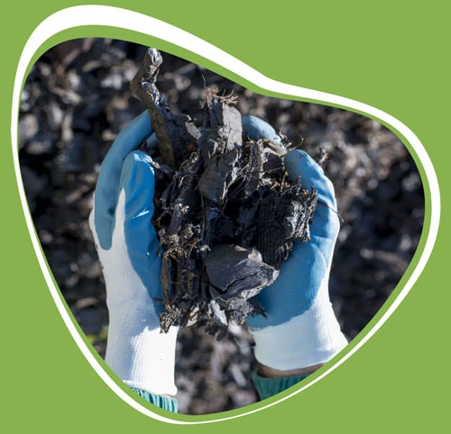 Foto que muestra dos manos con caucho de neumáticos viejos reciclado triturado 